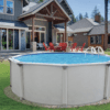 Above-ground PREMIUM POOL-Colombia 54"- 8" Resin Top Rail-SALT FRIENDLY in the backyard of a modern house, with red chairs arranged around a table nearby, surrounded by manicured lawn.